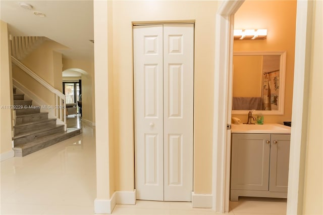 hall featuring light tile patterned floors and sink