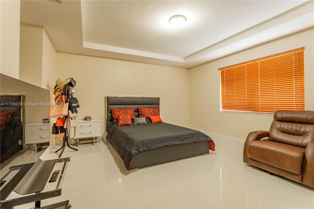 bedroom featuring tile patterned floors and a tray ceiling