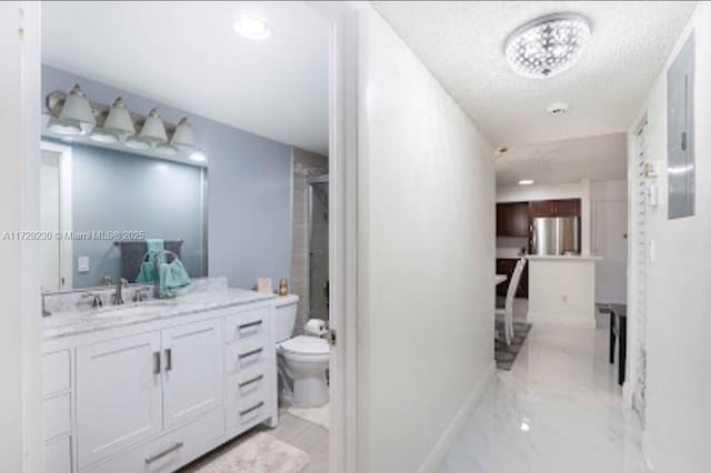 bathroom featuring toilet, vanity, a textured ceiling, and a shower with shower door