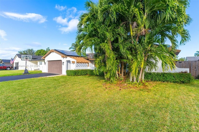 view of front of house with a garage, a front lawn, and solar panels