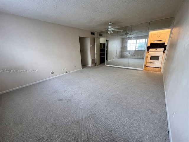 carpeted empty room featuring ceiling fan and a textured ceiling