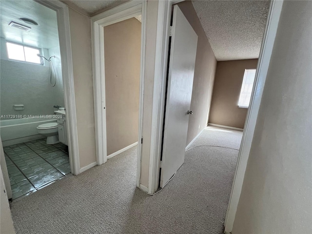 corridor with light carpet and a textured ceiling