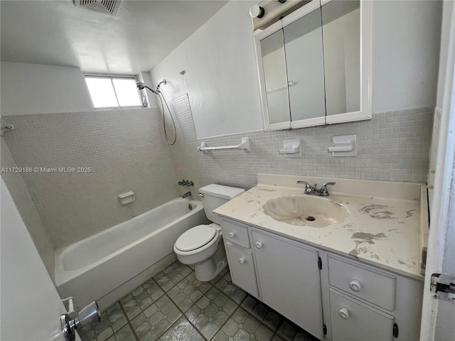 full bathroom featuring toilet, tiled shower / bath, tile patterned flooring, tile walls, and vanity