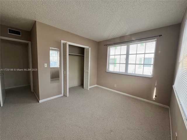 unfurnished bedroom with light colored carpet, a textured ceiling, and a closet