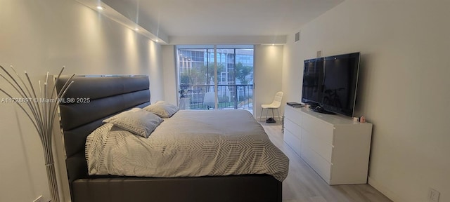 bedroom with light wood-type flooring and expansive windows