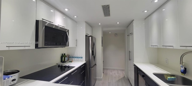 kitchen with sink, white cabinets, stainless steel appliances, and light wood-type flooring