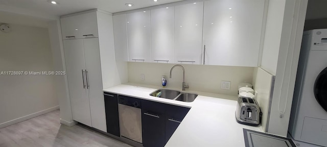 kitchen with sink, washer / dryer, white cabinetry, and light hardwood / wood-style floors