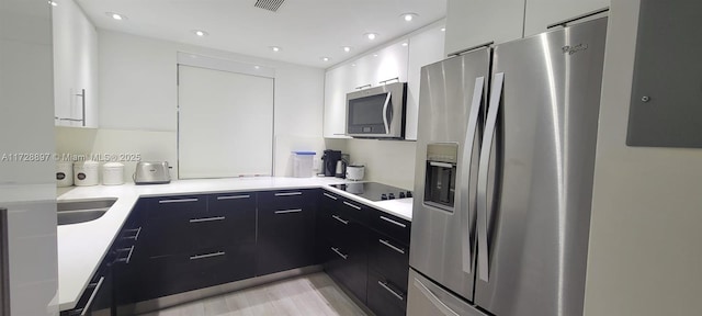 kitchen featuring light wood-type flooring, sink, stainless steel appliances, and white cabinetry