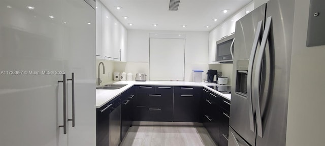 kitchen featuring white cabinetry, sink, light hardwood / wood-style flooring, and black appliances