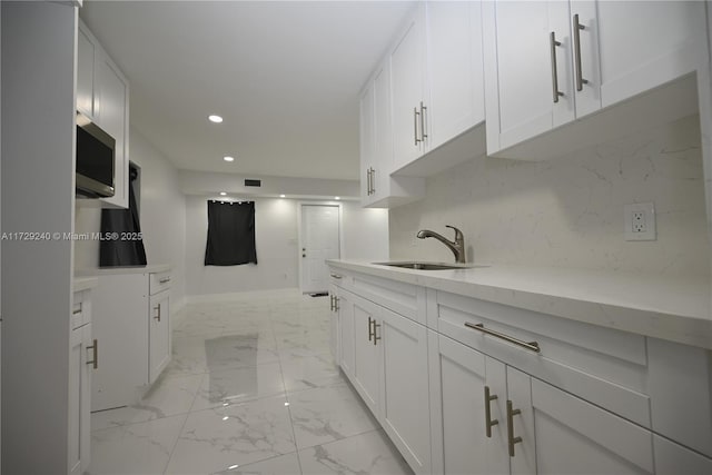 kitchen featuring light stone countertops, white cabinetry, and sink