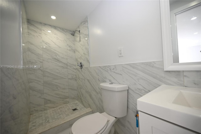 bathroom featuring tile walls, toilet, vanity, and a tile shower