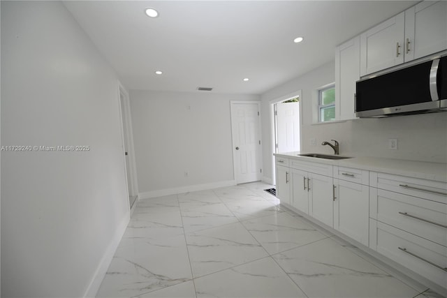 kitchen featuring backsplash, sink, and white cabinetry