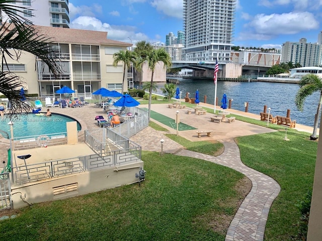 view of property's community with a swimming pool, a patio area, a water view, and a yard