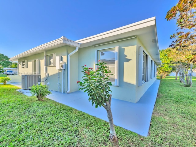 view of side of home featuring central AC and a lawn