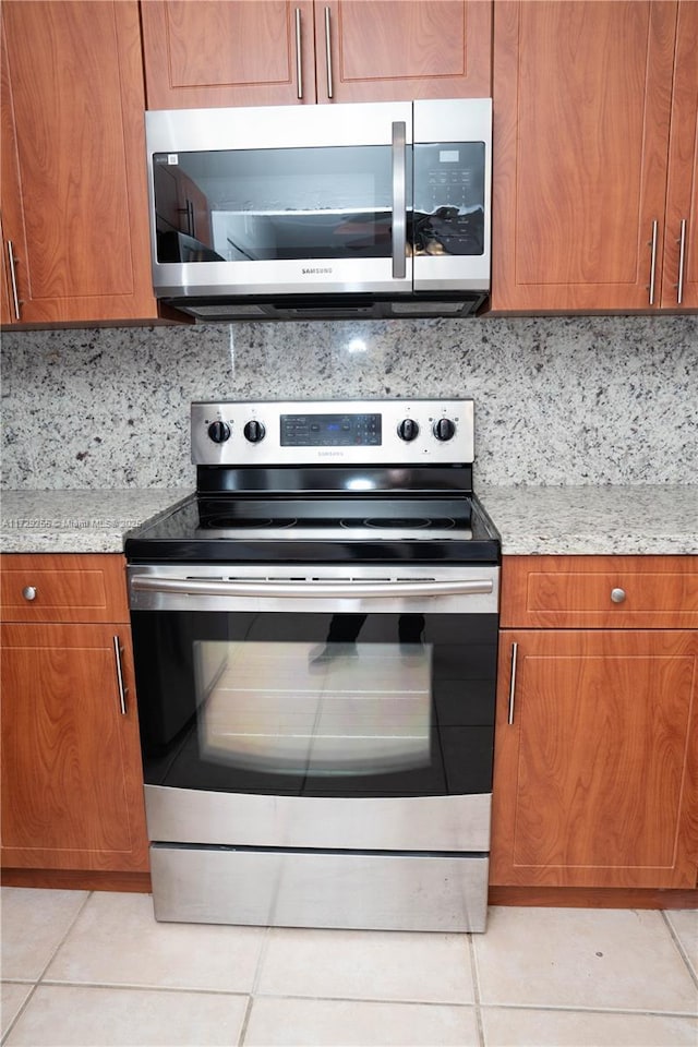 kitchen with stainless steel appliances, light tile patterned floors, and backsplash