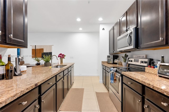 kitchen featuring light tile patterned floors, stainless steel appliances, light stone counters, dark brown cabinetry, and sink