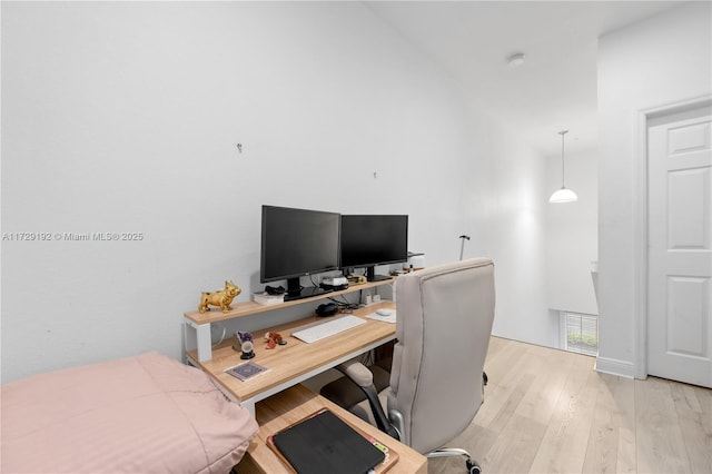 office space with light wood-type flooring and a high ceiling