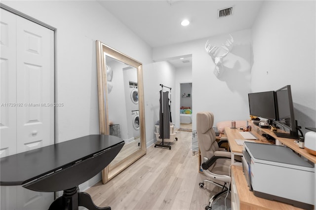 home office with light hardwood / wood-style floors and stacked washer / drying machine