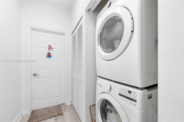 laundry area featuring stacked washer and clothes dryer and light hardwood / wood-style flooring