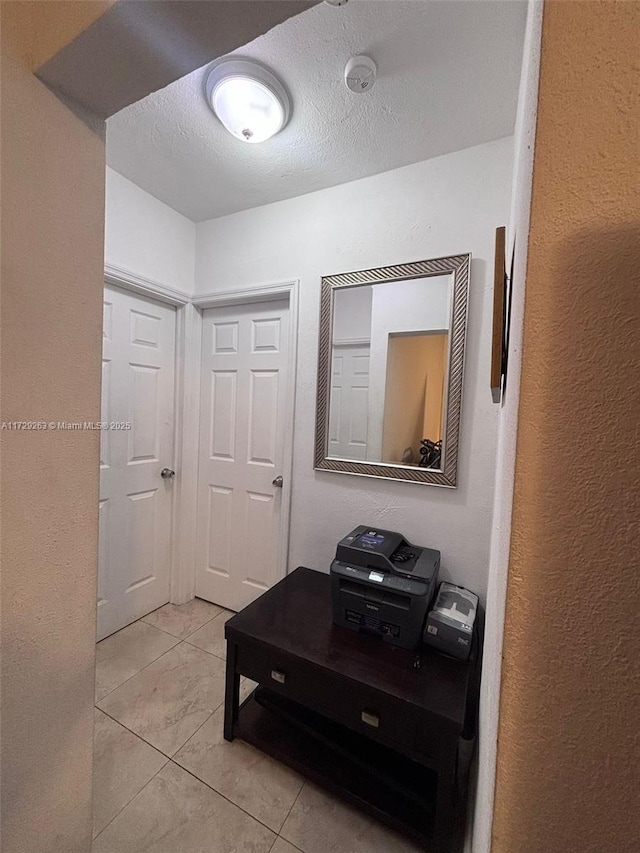 corridor featuring a textured ceiling and light tile patterned floors