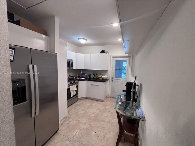 kitchen with light tile patterned floors, appliances with stainless steel finishes, white cabinetry, and tasteful backsplash