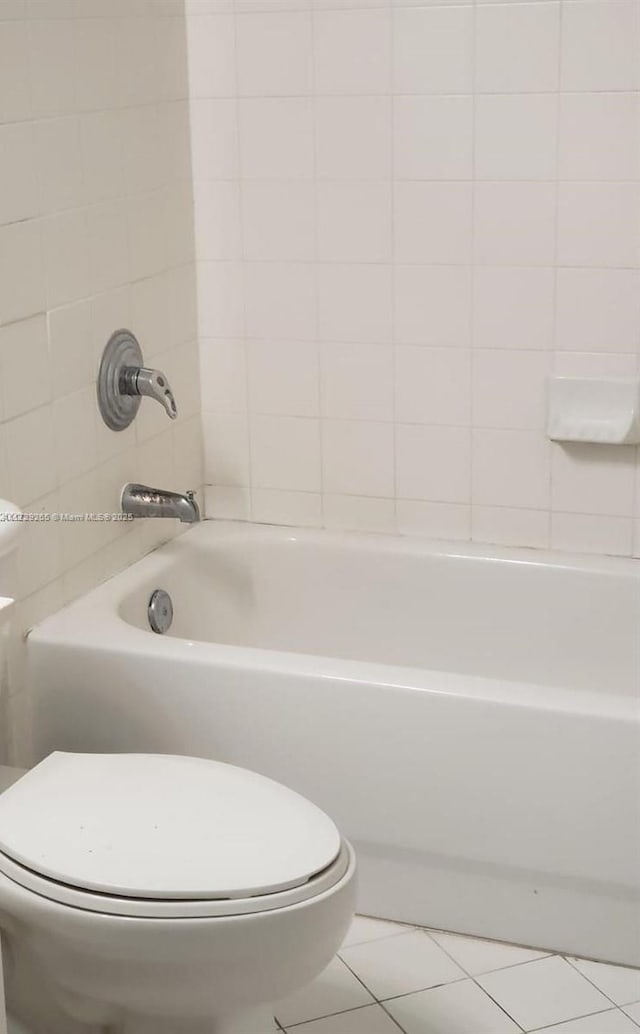 bathroom with toilet, tiled shower / bath combo, and tile patterned flooring