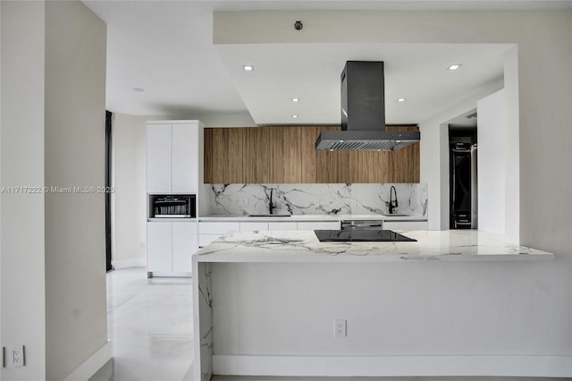 kitchen featuring tasteful backsplash, light stone countertops, white cabinets, island exhaust hood, and black electric cooktop