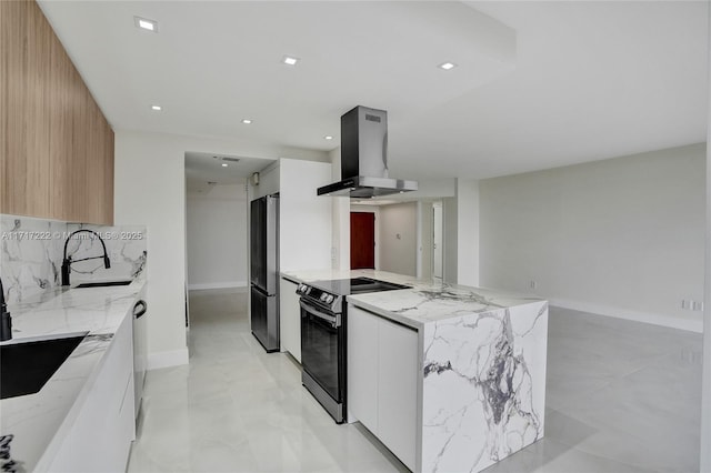 kitchen with island range hood, white cabinetry, sink, light stone counters, and stainless steel appliances