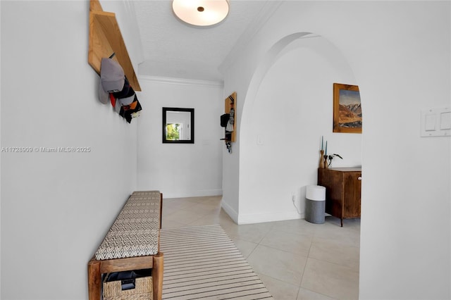 hall featuring a textured ceiling, light tile patterned flooring, and crown molding