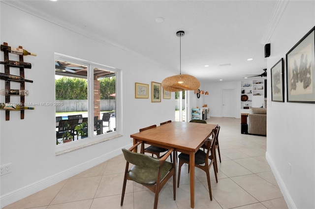 tiled dining space with ceiling fan, built in shelves, and ornamental molding