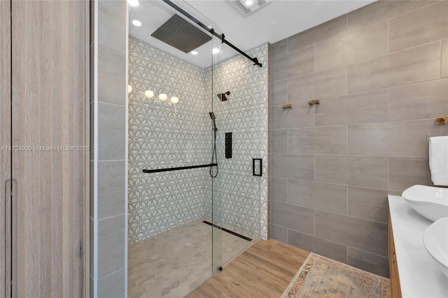 bathroom with a shower with shower door, hardwood / wood-style floors, and vanity