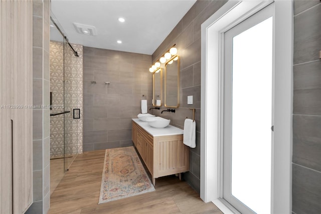 bathroom featuring an enclosed shower, vanity, and tile walls