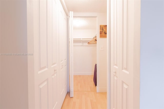 corridor featuring a textured ceiling and light wood-type flooring