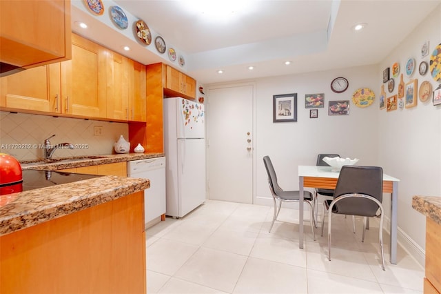 kitchen with backsplash, white appliances, light tile patterned flooring, light stone counters, and sink