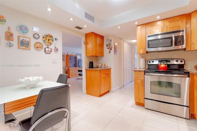 kitchen with light tile patterned floors, stainless steel appliances, decorative backsplash, and light stone countertops