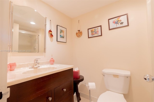 bathroom featuring toilet, vanity, and a shower with shower door