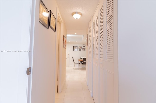 corridor featuring light tile patterned floors and a textured ceiling