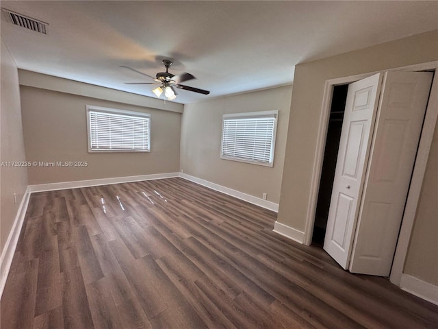 unfurnished bedroom featuring ceiling fan, dark hardwood / wood-style flooring, and multiple windows