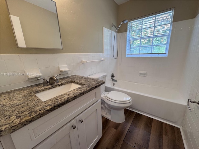 full bathroom featuring toilet, tiled shower / bath, tile walls, vanity, and wood-type flooring