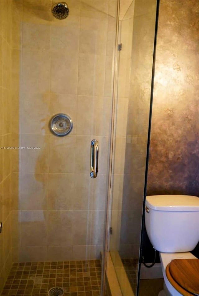 bathroom with toilet and a shower with door