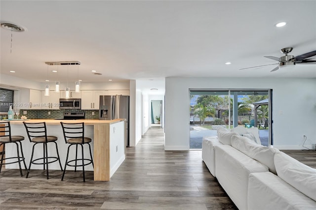 kitchen featuring tasteful backsplash, pendant lighting, white cabinetry, appliances with stainless steel finishes, and a kitchen breakfast bar