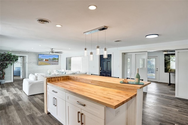 kitchen with white cabinets, a center island, wood counters, decorative light fixtures, and dark hardwood / wood-style flooring