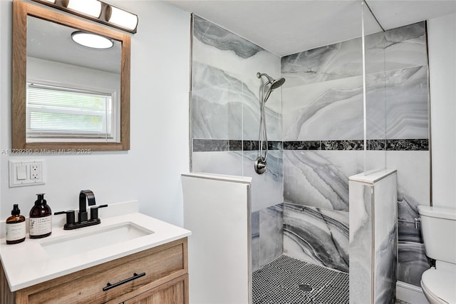 bathroom featuring toilet, vanity, and tiled shower