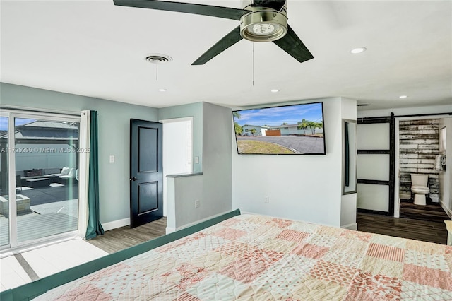 unfurnished bedroom featuring ceiling fan, a barn door, access to exterior, multiple windows, and hardwood / wood-style flooring