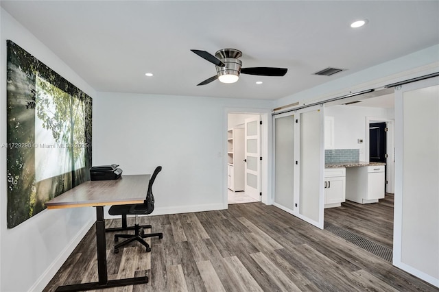 office space featuring ceiling fan, hardwood / wood-style floors, and a barn door