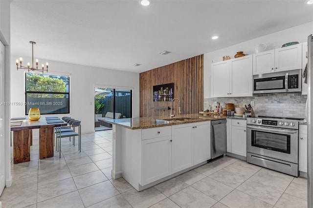 kitchen featuring kitchen peninsula, appliances with stainless steel finishes, dark stone counters, and white cabinetry