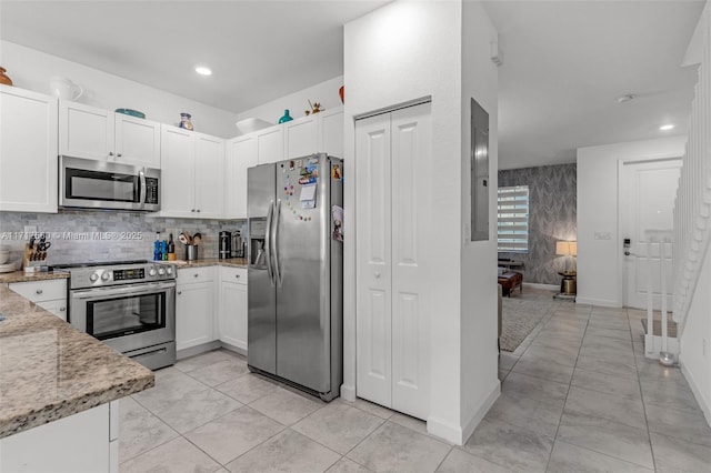 kitchen with white cabinets, appliances with stainless steel finishes, tasteful backsplash, light stone counters, and electric panel