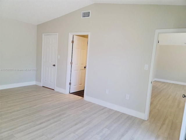 unfurnished room with lofted ceiling and light wood-type flooring