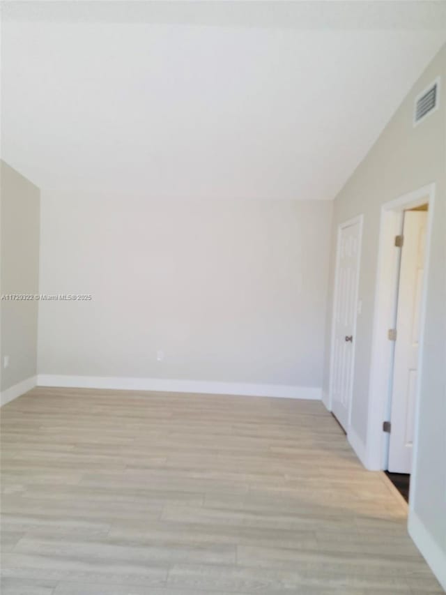 empty room featuring lofted ceiling and light hardwood / wood-style floors