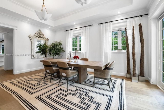 dining area featuring a tray ceiling, ornamental molding, and light hardwood / wood-style floors